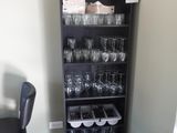des bouteilles et des verres posés sur une étagère dans une pièce où se trouve une chaise noire