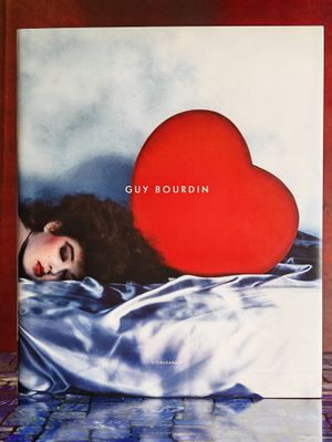un livre sur lequel figure la photo d'une femme allongée sur un lit orné d'un cœur rouge