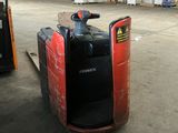 a forklift in a warehouse with pallets in the background