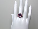une main blanche ornée d'une bague rose et bleue