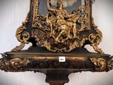 a gold clock on a shelf with a clock in the middle of it