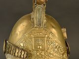 an antique gold helmet on a stand on a black background