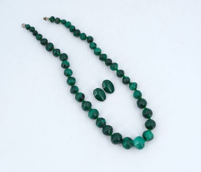 un gros plan d'un collier et de boucles d'oreilles verts posés sur une surface blanche