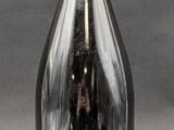 a black bottle with a red top on a gray surface