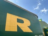 un gros camion vert avec un « R » jaune sur le côté