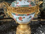 a gold and blue vase on a table with a wallpaper in the background