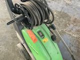une tondeuse à gazon verte à laquelle est raccordé un tuyau d'arrosage