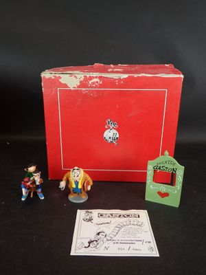 La boîte est rouge et contient deux petites figurines.