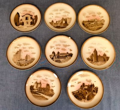 six assiettes ornées d'une image de château, posées sur une nappe bleue