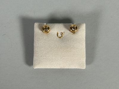 a close up of a pair of gold earrings on a white cloth