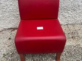 une chaise rouge posée sur un sol en béton, près d'un mur