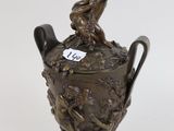 a bronze vase with a boy sitting on top of it