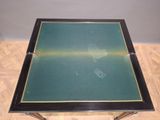 a black table with a green top on a wooden floor