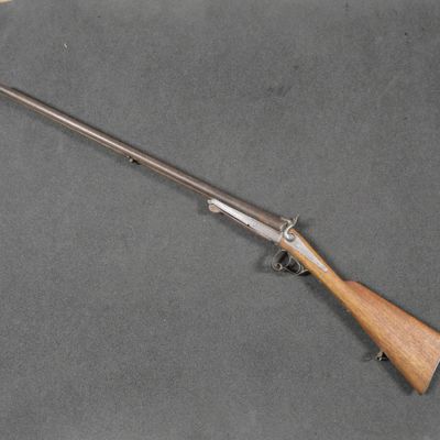 un fusil avec une crosse en bois posée sur une surface grise