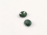 a pair of green tourmaline gems on a white surface