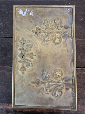 une boîte en métal ornée d'un motif, posée sur une table en bois