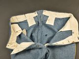 an old pair of blue jeans with white trims on a gray surface