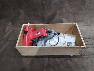 une boîte contenant un pistolet à colle rouge