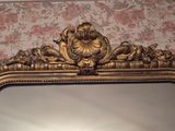 a mirror with a gold frame and a floral wallpaper