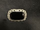a black stone ring sitting on top of a black leather surface