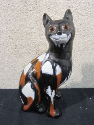 a black and orange cat statue sitting on a black surface