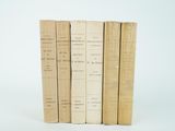 several old books are stacked on top of each other on a white surface
