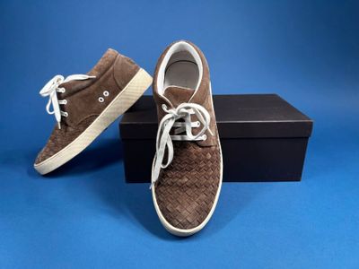 men ' s brown sued sneakers with white laces on a blue background