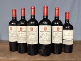 six bottles of red wine are lined up on a wooden table