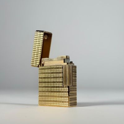 une photo d'un étui à cigarettes en or posé sur une table blanche