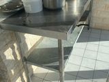 une table en acier inoxydable sur laquelle sont posés des casseroles et des poêles