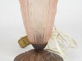 a pink glass vase sitting on top of a wooden stand