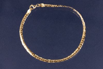 un gros plan d'un bracelet à maillons dorés sur fond bleu