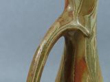 a brown and green vase with a handle sitting on a table