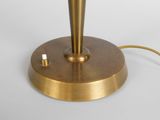 a gold table lamp that is on a white surface
