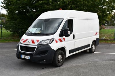 une camionnette blanche garée sur un parking avec des arbres en arrière-plan