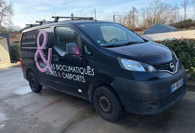 a black van parked in a parking lot with a pink ribbon on the side of it