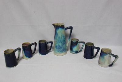 a group of blue and white coffee mugs and a pitcher