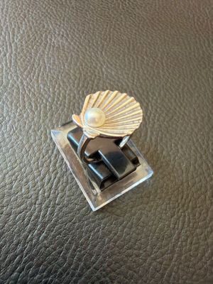 a ring with a shell on top of it on a leather surface
