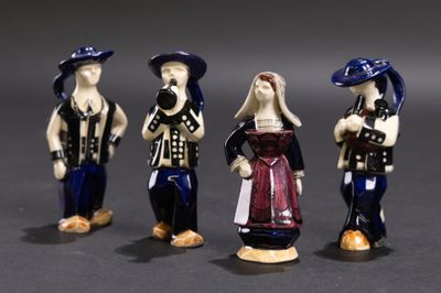trois figurines représentant des personnes vêtues de tenues et coiffées de chapeaux différents