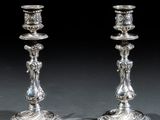 une paire de bougeoirs anciens en argent posés sur une table devant un fond noir