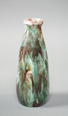 un vase vert et marron posé sur une surface grise