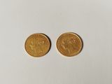 two gold sovereigns on a white surface