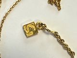 un collier en or orné d'une montre, posé sur un fond blanc
