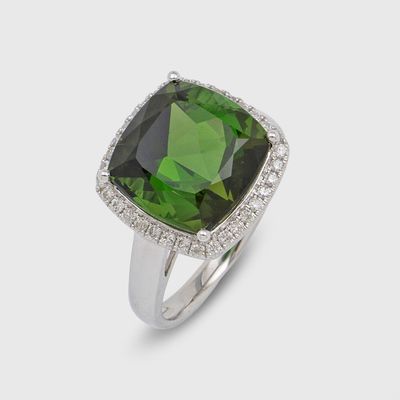 a close up of a ring with a green stone surrounded by diamonds