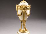 a white and gold vase on a white table