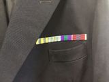 a close up of a suit jacket with a colorful ribbon in the pocket