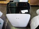 a white and black air purifier sitting on the floor next to other items