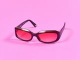 un gros plan sur une paire de lunettes de soleil sur fond rose