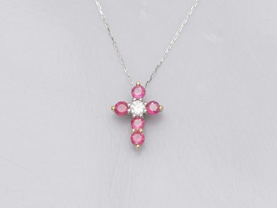 a small pink cross necklace on a silver chain