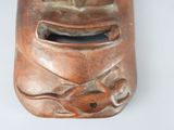 a brown mask with fish on it on a white surface